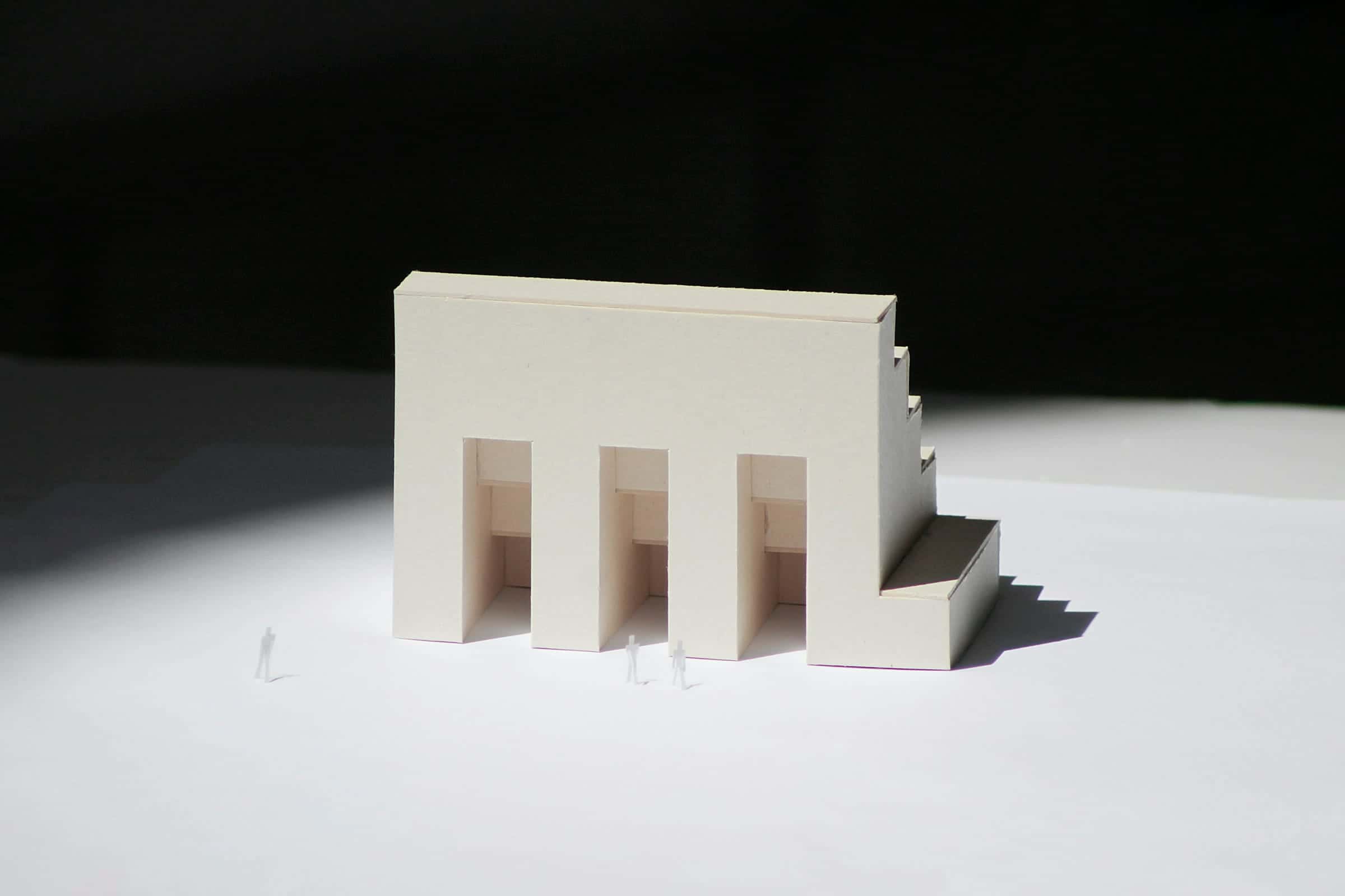 A white architectural model with small figures, lit from one side.