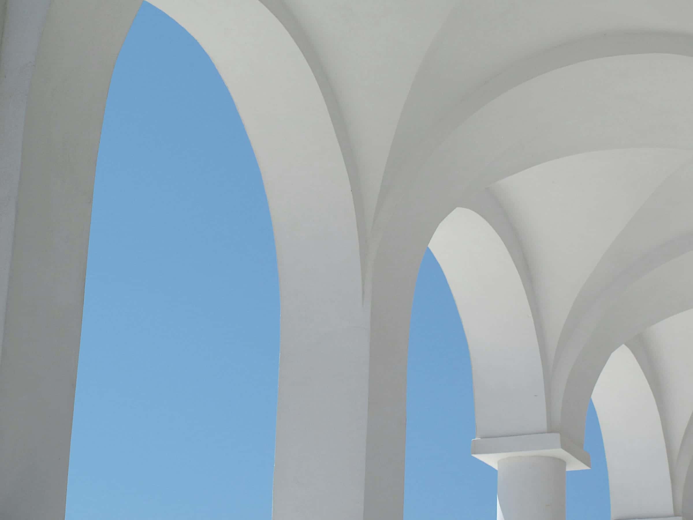 White vaulted arches opening onto a clear blue sky.