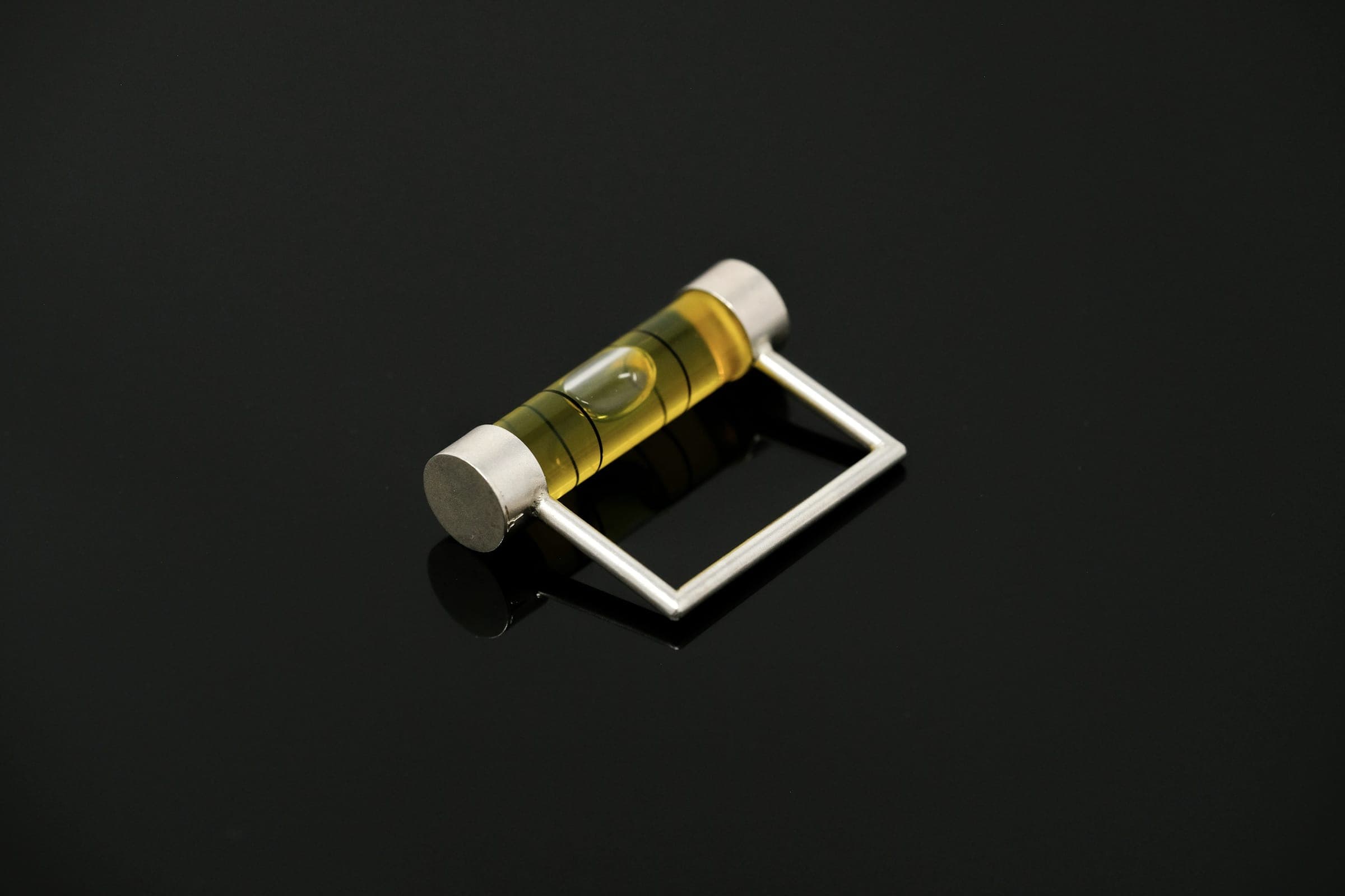 A small spirit-level vial in a metal frame on a black surface.
