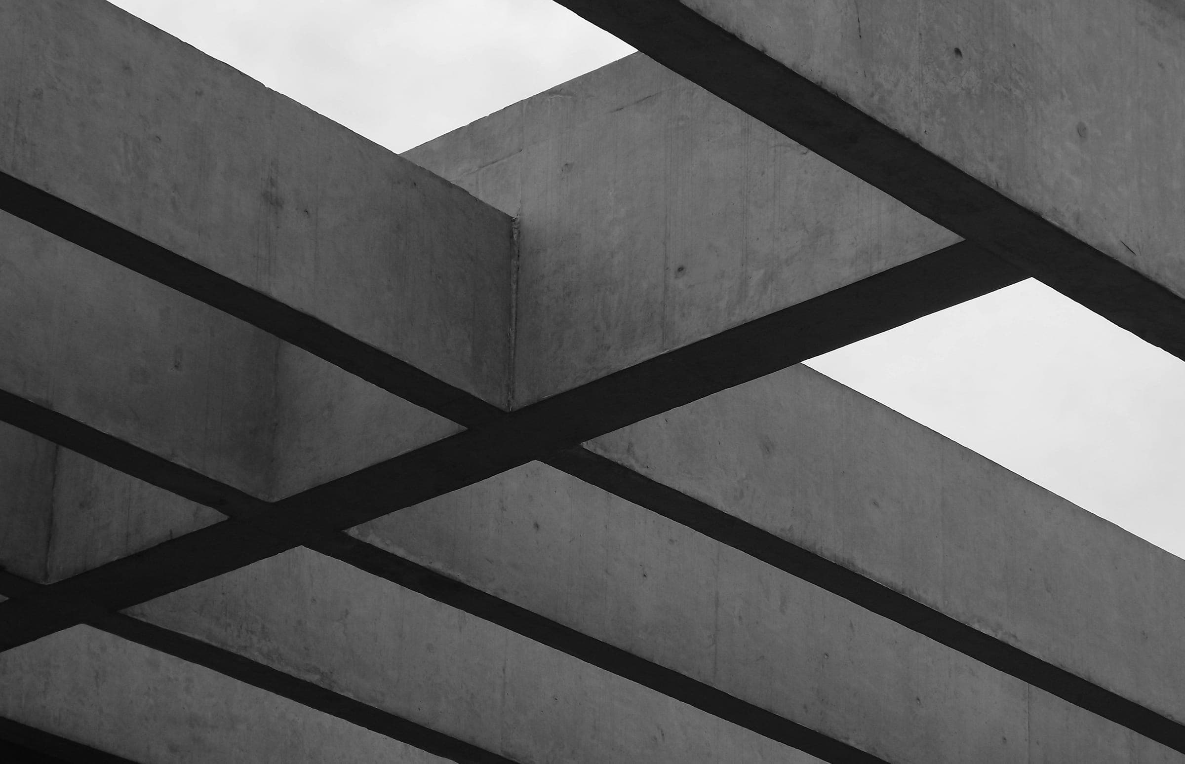 Crossing concrete beams against a pale sky, in black and white.