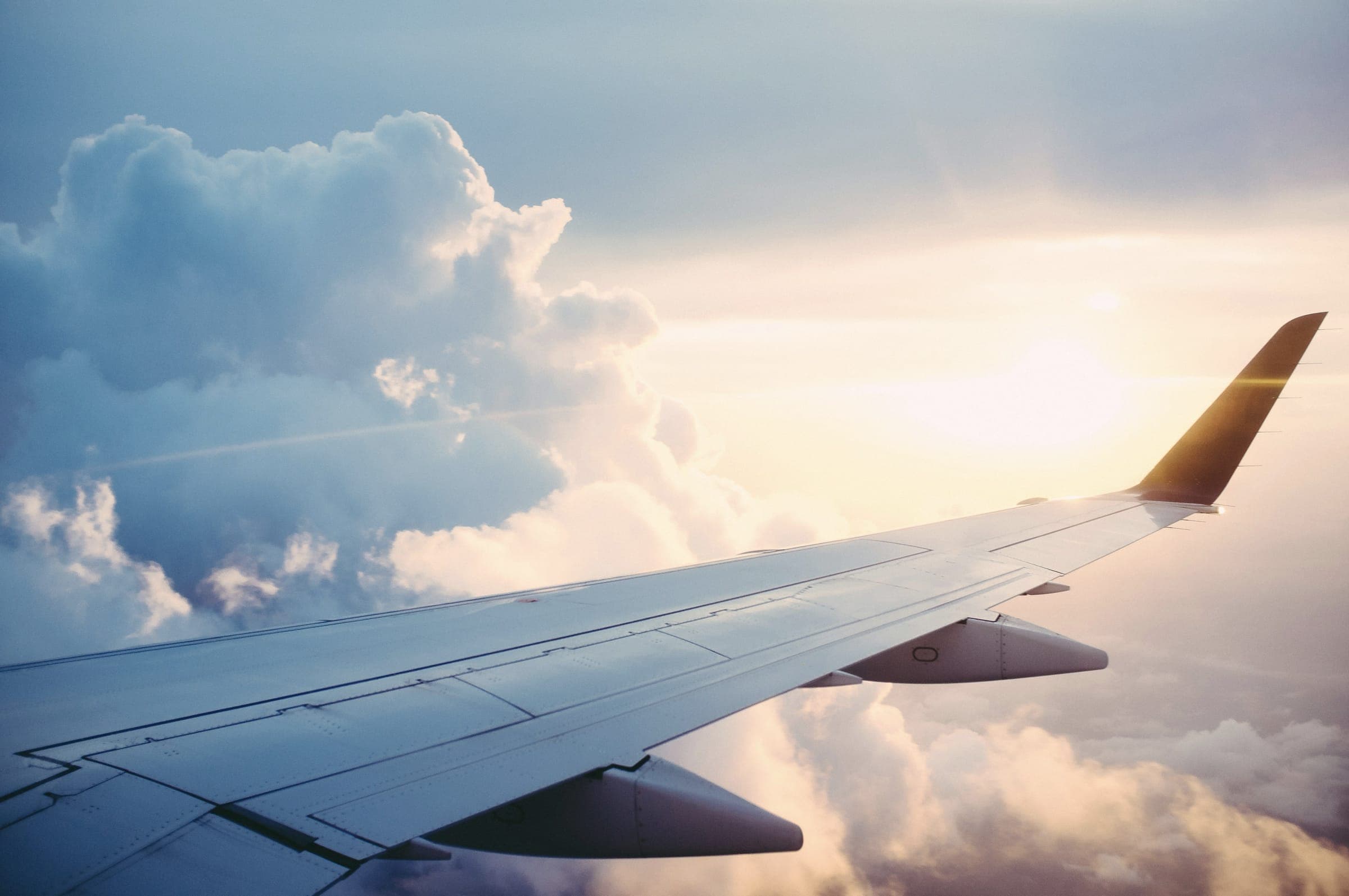 An aircraft wing above sunlit clouds.